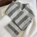 Detailed view of a soft grey striped knitted cross neck warmer with metallic logo plate - Criss Cross Halter / Grey Stripe