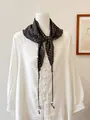 Dettaglio di un foulard triangolare vintage a fiori con lacci di perline su camicia. - Floreale Caffè