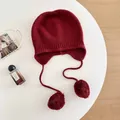 Close-up detail of a soft burgundy wool knitted earflap hat with decorative pom-poms. - M (56-58cm) / Red