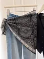 Black and white paisley triangle silk scarf styled as a chic waist accessory over denim - Black Paisley