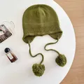 Detailed macro view of olive green wool knit balaclava with pom-poms. - M (56-58cm) / Green
