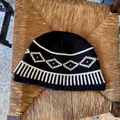 Vista dettagliata del berretto in lana lavorata a maglia Fair Isle bianco e nero su sedia. - Taglia unica / Nero