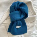 Sciarpa invernale in maglia blu pavone con etichetta del marchio su cappotto bianco - 160x20cm / Blu Klein