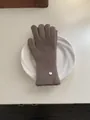 Soft brown knitted winter wool glove with silver brand tag on a white ceramic plate - Gloves-mocha color