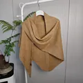Detail van gemberkleurige gebreide sjaal met lovertjes op een hanger met kamerplant - Tops / 175x75cm / camel