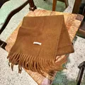 Primer plano de una bufanda de mezcla de lana marrón con flecos suaves y detalle de etiqueta. - 200cm / Caramelo