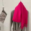 Détail d'une écharpe en laine fuchsia vibrante avec franges sur un manteau gris élégant. - Rose rouge / 185cm