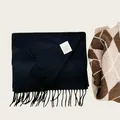 Close-up detail of 100% Australian wool scarf in navy blue featuring soft tassels and label - Black