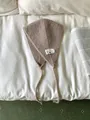 Vintage taupe knitted ear warmer with a decorative label on white bedding sheets - One Size / Khaki