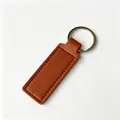 Llavero rectangular de cuero PU marrón con anillo plateado y bordes cosidos con pespuntes. - Marrón