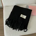 Thick black wool scarf featuring tassel fringe and minimalist studio brand label - Black