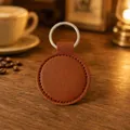 Porte-clés rond en cuir PU marron avec anneau argenté sur une table en bois chaleureuse - Marron