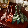Assorted elegant printed silk scarf keychains with gold rings displayed on a vintage vanity - Random Mixed Colors