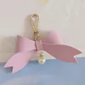 Detailed view of a cute pink PU leather bow keychain featuring a delicate pearl pendant - Purple