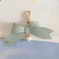 Close-up showing the fine texture of the light blue PU leather bow keychain with pearl - Blue