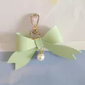 Detailed view of a mint green PU leather bow keychain with a white pearl pendant - Green