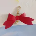 Gros plan sur un porte-clés nœud en similicuir rouge avec perle et fermoir - Rouge