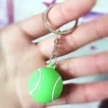 Primer plano de un llavero de mini pelota de tenis verde de PVC blando. - Pelota de tenis