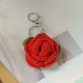 Handmade red crocheted rose keychain with green leaves on a clean white paper background - Red