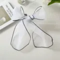 Elegant white organza hair ribbon with black piped edges tied in a delicate bow knot. - One Size / White
