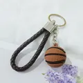 Primer plano de un llavero de baloncesto 3D con correa tejida marrón en fondo blanco - Marrón