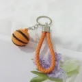 Detalle del amuleto de baloncesto 3D con llavero de correa de cuero trenzado naranja brillante. - Naranja