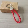 Vista detallada de un llavero de cuero trenzado rojo con un anillo de metal plateado - Rojo Sólido