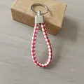 Detalle del llavero de cuerda de cuero trenzado rojo y blanco con anillo de metal plateado - 白加红款