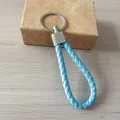 Detalle de llavero de cuero trenzado azul con anillo metálico y caja de regalo - Azul Claro