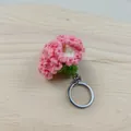 Nahaufnahme eines handgefertigten rosa gehäkelten Nelken-Schlüsselanhängers auf Holz - Rosa