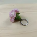 Handgefertigter Schlüsselanhänger mit rosa Häkelnelke auf natürlichem Holzbrett - Hellviolett