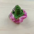 Gedetailleerde macro-opname van een handgemaakte roze en groene gehaakte anjer-sleutelhanger. - Rozerood