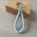 Elegante llavero de cuero trenzado azul y blanco con un resistente anillo de metal plateado - Estilo Blanco y Azul Claro