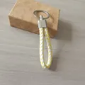 Llavero de cuerda trenzada en cuero amarillo y blanco con anillo de metal plateado - Estilo Blanco y Amarillo