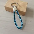 Elegante llavero de cuero trenzado azul y negro con anillo de metal plateado - Estilo Azul Claro y Negro
