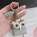 Vue détaillée d'un joli porte-clés hibou en cuir gris avec pompon décoratif et fermoir doré - Gris
