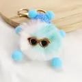 Macro view of a fluffy blue plush monster keychain with sunglasses and a gold clasp - Number 2