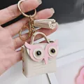 Vue détaillée d'un adorable mini porte-monnaie chouette en cuir avec pompon élégant - Beige