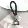 Close-up detail of a premium black braided leather keychain with gunmetal horseshoe buckle - Black