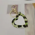 Gros plan du porte-clés miroir cœur imprimé léopard avec détails en métal doré. - Style Cœur / Vert