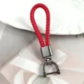 Macro view of a red braided leather keychain with a metallic gunmetal horseshoe buckle - Red