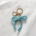 Hand-crocheted blue and white yarn bow keychain with pearl detail for cute bag charm - Gradient Blue