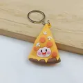 Close-up of a cute cartoon pizza slice keychain with a smiling face on a wooden surface. - Pizza Keychain