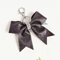 Porte-clés élégant en forme de nœud à paillettes violettes avec centre en strass - Noir
