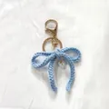 Handmade light blue crochet bow keychain accessory with a delicate white faux pearl charm - Dark Blue