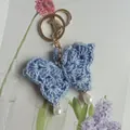 Handmade light blue crochet butterfly keychain featuring elegant white pearl charms - Blue