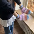 Close-up of colorful fuzzy knit mittens worn by a person in a cozy winter indoor setting - Blue Edge Pink Gloves