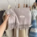 Detailed view of a soft mauve knitted scarf with fringes and a minimalist brand tag. - Oatmeal