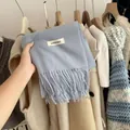 Close-up detail of a soft blue knitted scarf with fringes and a minimalist brand tag - Sky Blue