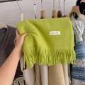 Detailed view of a bright lime green knit scarf with long tassels and a small white label - 194cm / Mustard Green